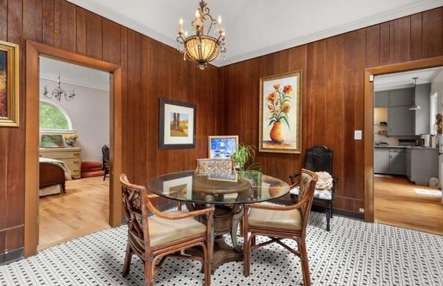 dining area featuring wood walls, crown molding, and an inviting chandelier