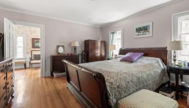 bedroom with light hardwood / wood-style flooring, multiple windows, and crown molding