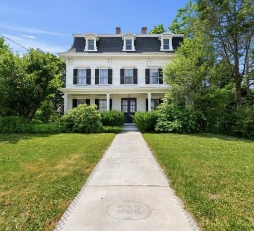 italianate home featuring covered porch and a front yard