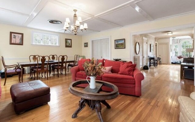 living room featuring light hardwood / wood-style flooring, coffered ceiling, and a notable chandelier