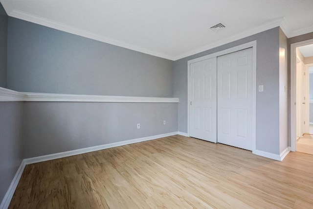 unfurnished bedroom with visible vents, light wood-type flooring, baseboards, and ornamental molding