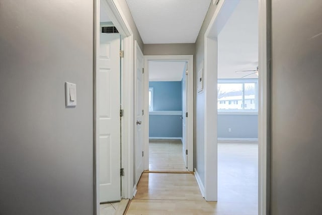 corridor with light wood finished floors and baseboards