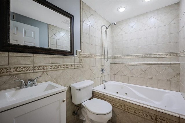 bathroom featuring toilet, vanity, tile walls, and a combined bath / shower with jetted tub