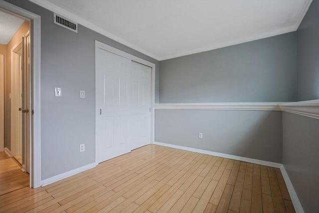 unfurnished bedroom with a closet, visible vents, baseboards, and wood finished floors