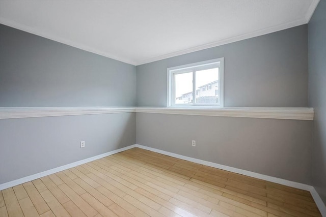 spare room with crown molding, baseboards, and wood finished floors