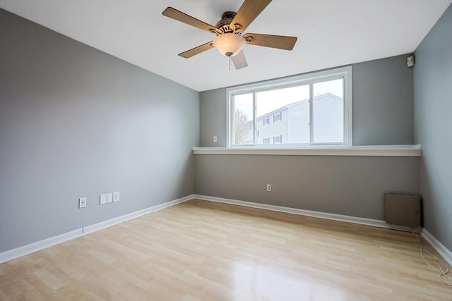 empty room with ceiling fan, baseboards, and wood finished floors