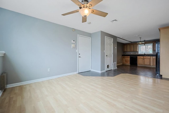 unfurnished living room featuring dark wood-type flooring, baseboards, visible vents, and a sink