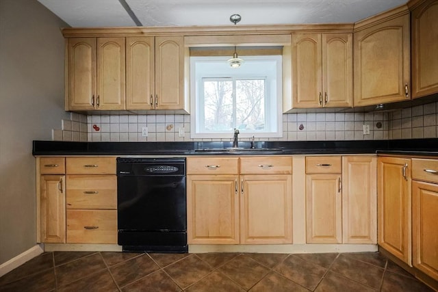 kitchen featuring dark countertops, dark tile patterned flooring, black dishwasher, and a sink