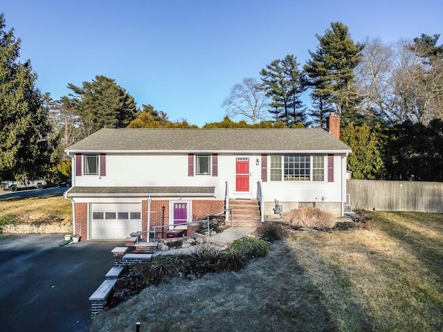 view of front of house featuring driveway, a chimney, an attached garage, fence, and brick siding