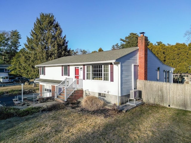 view of front facade with a front lawn, a chimney, and fence