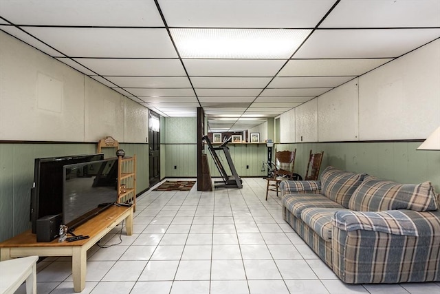 living room featuring a paneled ceiling, a wainscoted wall, and light tile patterned floors