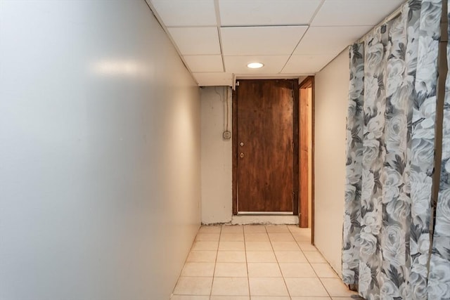 corridor featuring a paneled ceiling and light tile patterned floors