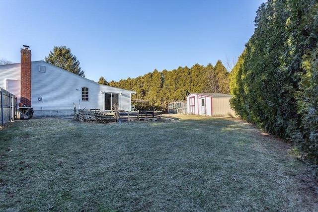 view of yard featuring an outbuilding, a storage unit, and fence