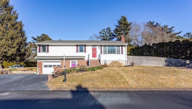 view of front of property with driveway, a chimney, an attached garage, a front yard, and brick siding