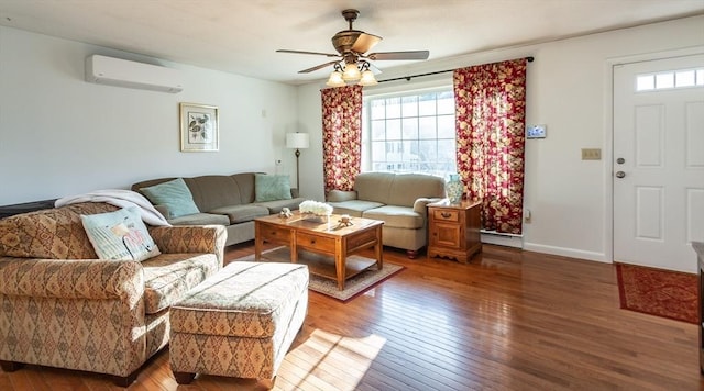 living room featuring a baseboard heating unit, a ceiling fan, baseboards, hardwood / wood-style floors, and a wall mounted air conditioner