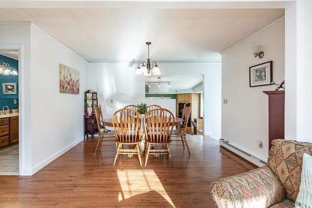 dining space with light wood finished floors, a baseboard radiator, a chandelier, and crown molding