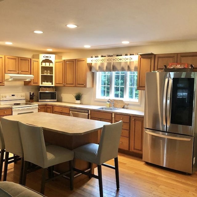 216 Fairbanks St, West Boylston, MA 01583 - kitchen with appliances with stainless steel finishes, under cabinet range hood, a breakfast bar, light countertops, and light wood-type flooring