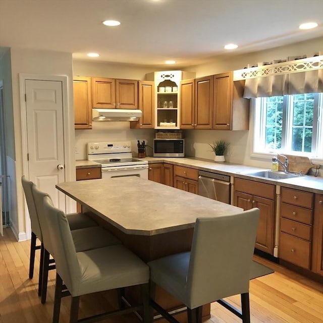 216 Fairbanks St, West Boylston, MA 01583 - kitchen with appliances with stainless steel finishes, under cabinet range hood, a kitchen bar, light wood finished floors, and recessed lighting