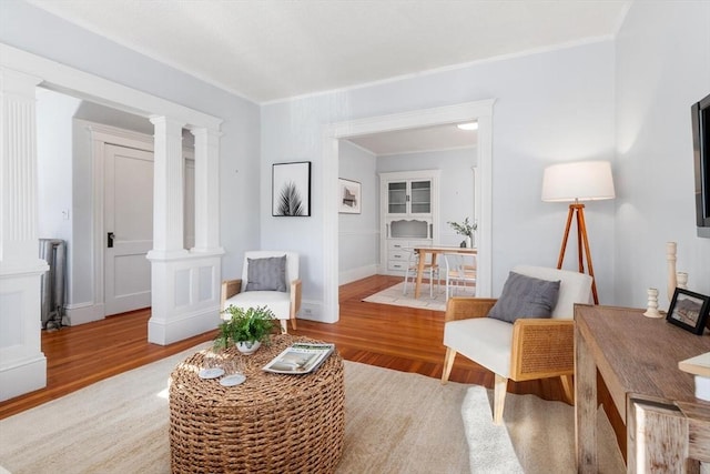 sitting room with ornamental molding, radiator heating unit, ornate columns, and light hardwood / wood-style floors