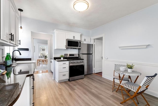 kitchen featuring white cabinets, decorative light fixtures, light hardwood / wood-style floors, and appliances with stainless steel finishes