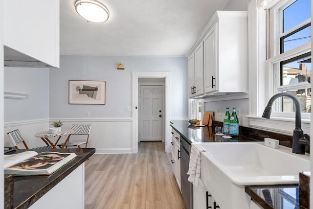 kitchen with sink, plenty of natural light, white cabinetry, and light hardwood / wood-style flooring