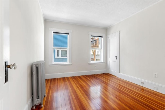 spare room with radiator heating unit, a textured ceiling, and wood-type flooring