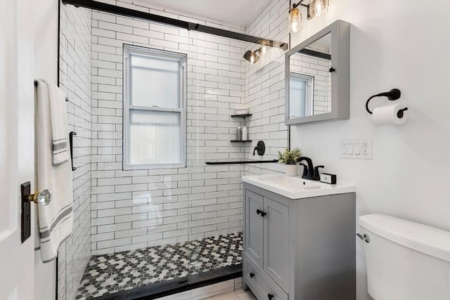 bathroom with vanity, toilet, and a tile shower