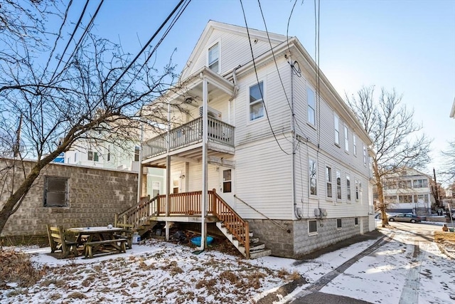 snow covered back of property with a balcony