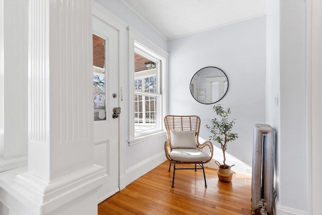 sitting room with wood-type flooring, radiator heating unit, and crown molding