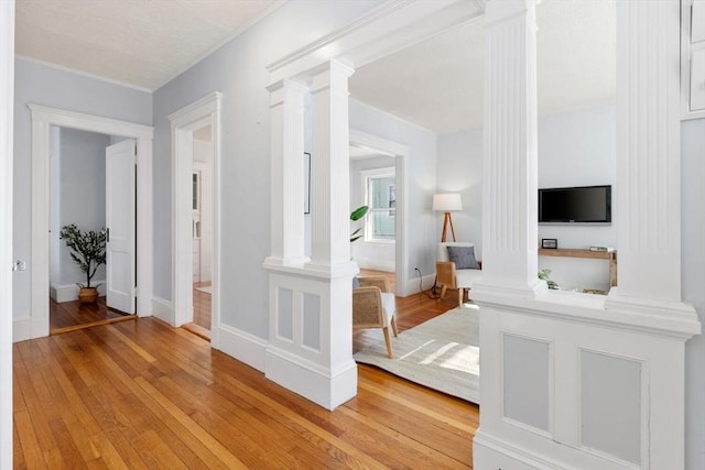 hall with decorative columns and light hardwood / wood-style flooring