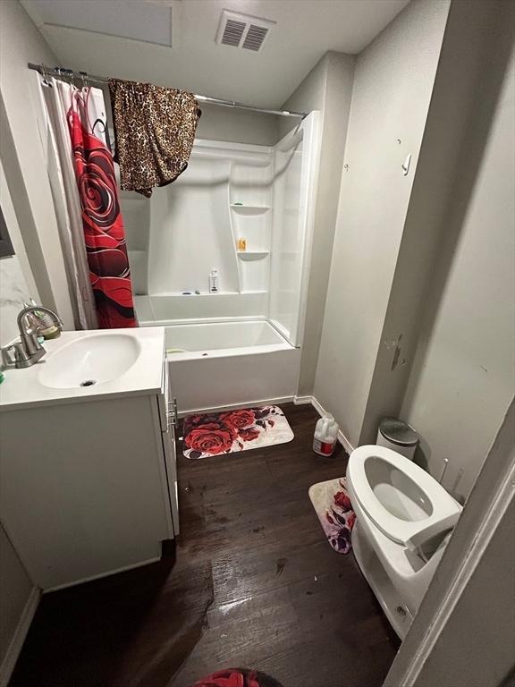 full bathroom with hardwood / wood-style flooring, vanity, toilet, and shower / bath combo with shower curtain