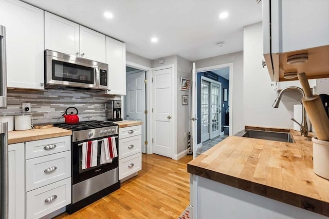 kitchen with sink, white cabinetry, appliances with stainless steel finishes, and wooden counters