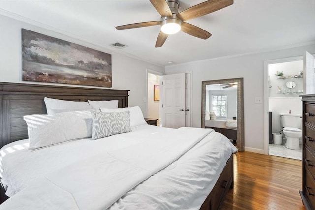 bedroom with ceiling fan, ensuite bath, dark hardwood / wood-style floors, and crown molding