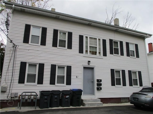 view of front facade featuring entry steps and a chimney