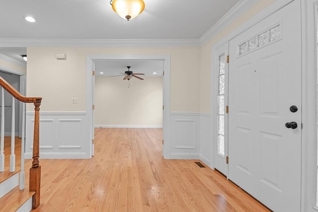 foyer with ornamental molding and light hardwood / wood-style floors