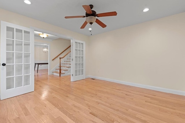 unfurnished room featuring ceiling fan with notable chandelier, light hardwood / wood-style flooring, and french doors