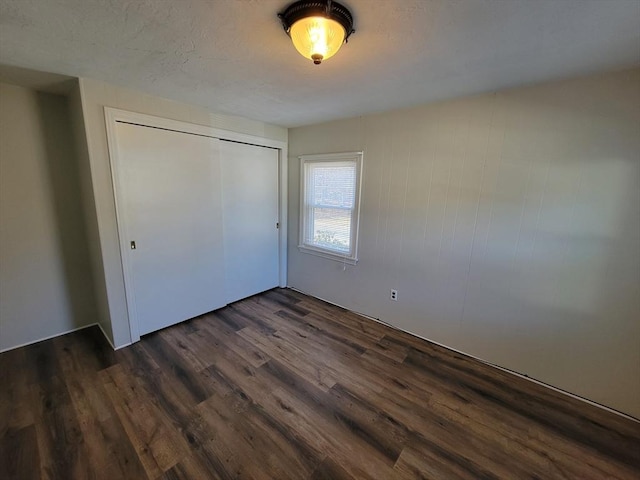 unfurnished bedroom with dark hardwood / wood-style flooring and a closet