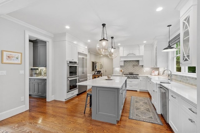 159 Marked Tree Rd, Needham, MA 02492 - kitchen with appliances with stainless steel finishes, gray cabinetry, backsplash, light countertops, and a center island
