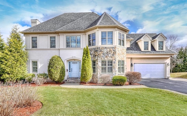 view of front of property featuring aphalt driveway, stone siding, a front yard, and stucco siding