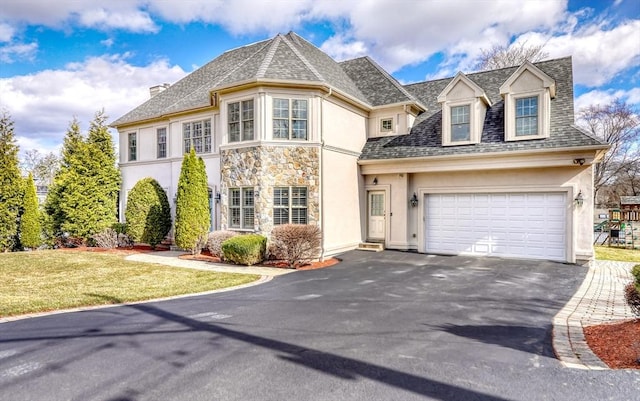 view of front facade with aphalt driveway, stone siding, a front lawn, and stucco siding