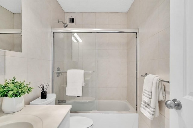 full bathroom with vanity, toilet, shower / bath combination with glass door, and tile walls