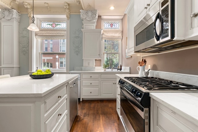 kitchen with white cabinets, sink, decorative light fixtures, stainless steel appliances, and dark hardwood / wood-style floors