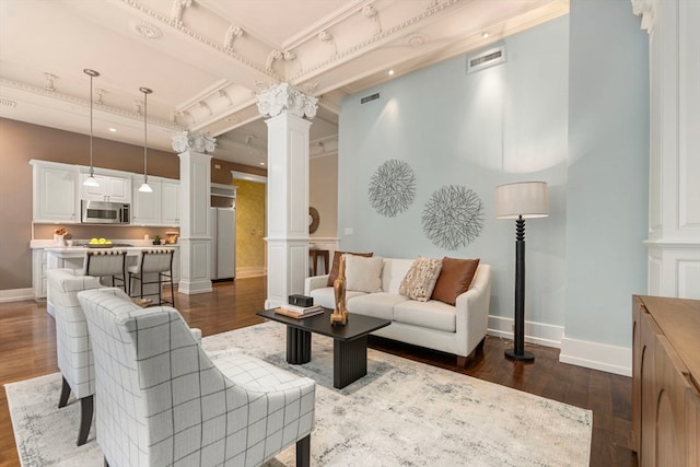 living room featuring ornate columns, dark hardwood / wood-style floors, crown molding, and beam ceiling