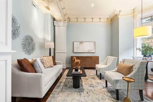 living area featuring ornamental molding, dark wood-type flooring, and ornate columns