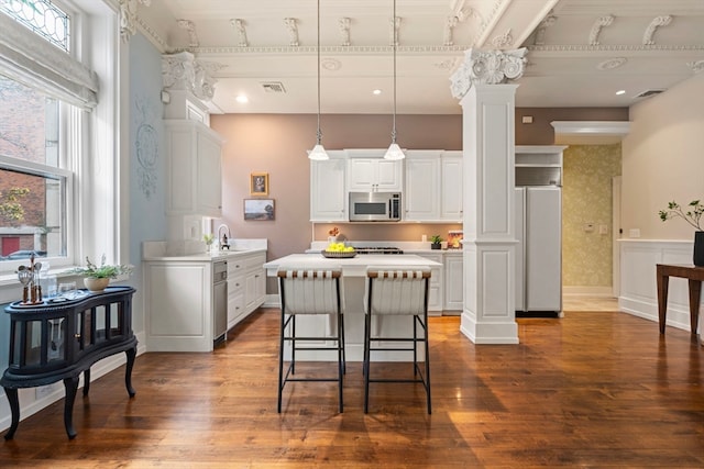 kitchen with white cabinets, dark hardwood / wood-style floors, decorative columns, and pendant lighting