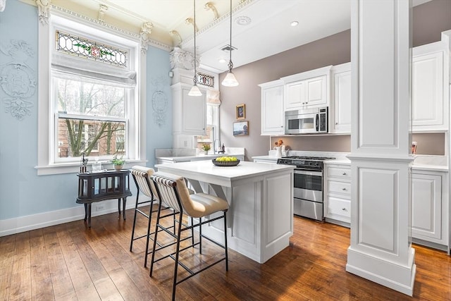 8 Garrison St Unit 104, Boston, MA 02116 - kitchen with stainless steel appliances, a center island, light countertops, dark wood-style flooring, and ornamental molding