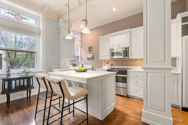 kitchen with appliances with stainless steel finishes, a center island, white cabinets, and dark hardwood / wood-style flooring