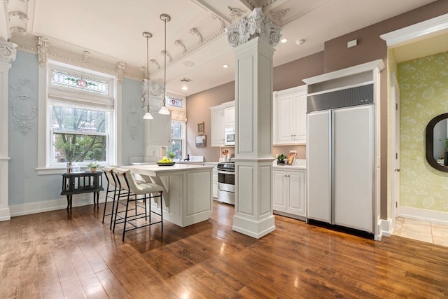 kitchen featuring a kitchen island, dark wood-type flooring, ornate columns, white cabinetry, and paneled fridge