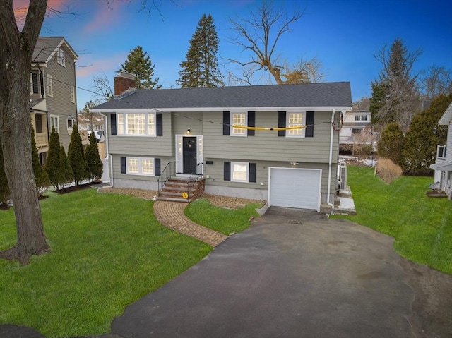 bi-level home with a garage and a lawn