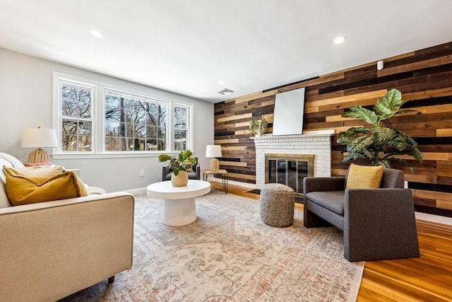 living room featuring hardwood / wood-style flooring, a brick fireplace, and wooden walls